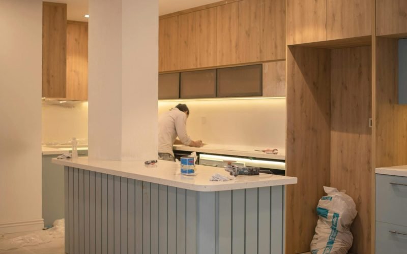 Contemporary kitchen undergoing renovation with wooden cabinets and clean design.