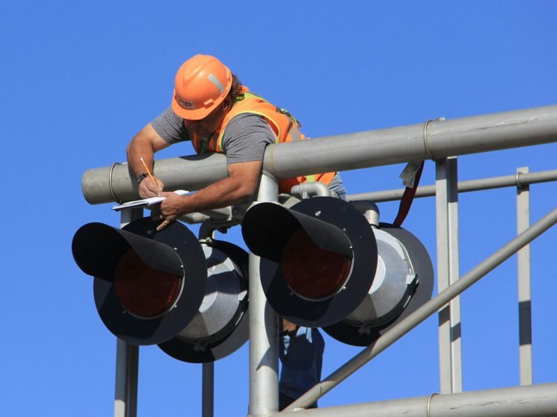 Photo by Dan Loran man in orange helmet climbing on white metal bar during daytime